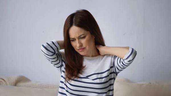 Засмучена жінка торкається шиї, страждаючи від болю — стокове фото
