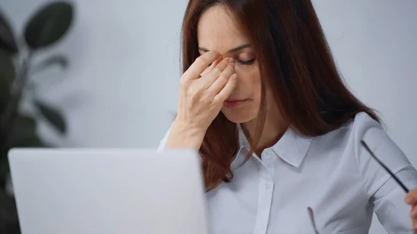 Mujer de negocios cansada con los ojos cerrados que sufren de dolor de cabeza en la oficina - foto de stock