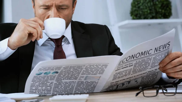 Hombre de negocios beber café y leer noticias económicas en la oficina — Stock Photo