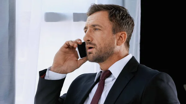 Businessman in formal wear talking on smartphone in office — Stock Photo