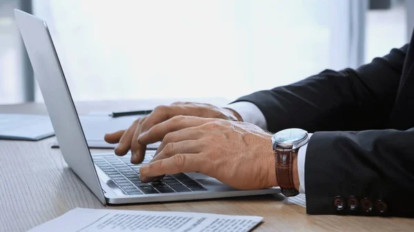 Обрізаний вид бізнесмена в наручному годиннику на ноутбуці в офісі — стокове фото