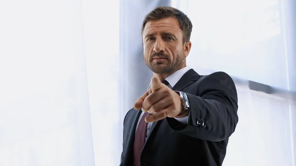 Confident businessman looking at camera and pointing with finger — Stock Photo