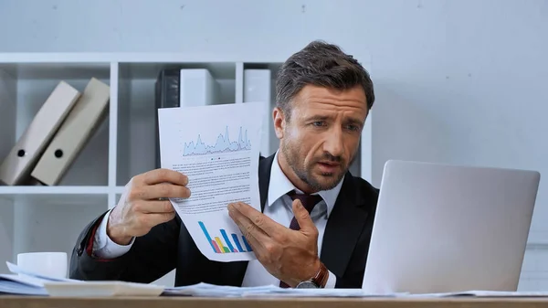 Businessman showing infographics during video call on laptop — Stock Photo