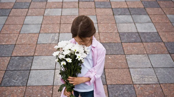 Vista de ángulo alto del niño oliendo mientras que las flores fuera - foto de stock