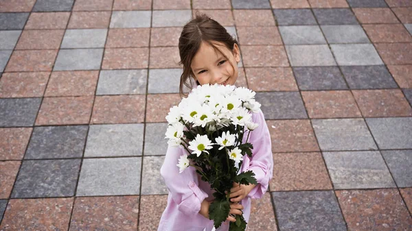 High angle view of happy kid holding bouquet of while flowers outside — Fotografia de Stock