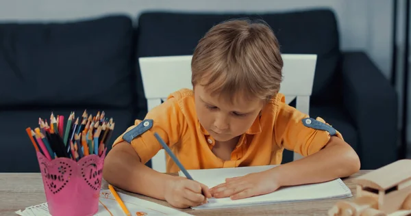 Малюнки на папері біля дерев'яної іграшкової машини та власника пера з кольоровими олівцями на столі. — стокове фото