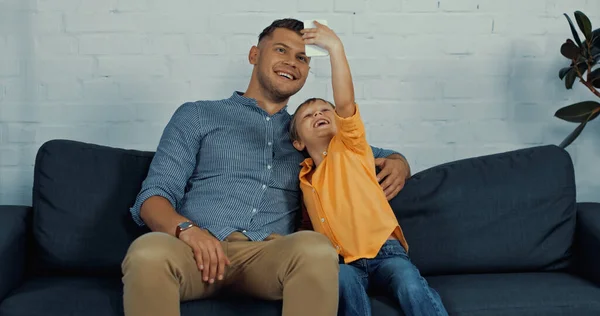 Happy father and cheerful son smiling while taking selfie at home — Stock Photo