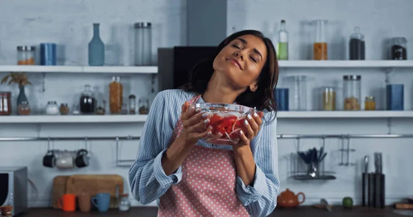 Zufriedene Frau mit geschlossenen Augen hält Schüssel mit frischem vegetarischen Salat in der Küche — Stockfoto