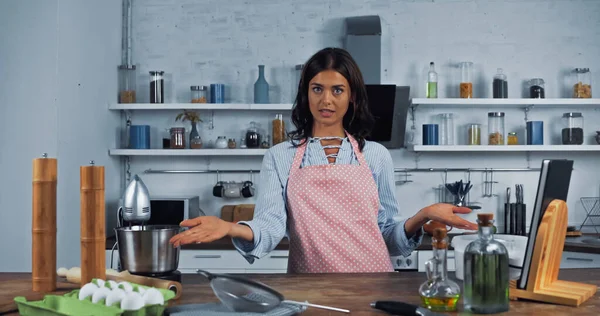 Vlogger culinaire pointant vers les ingrédients et les ustensiles de cuisine tout en regardant la caméra — Photo de stock