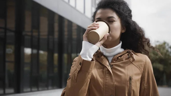 Молодая африканская американка пьет кофе, чтобы выйти на улицу — стоковое фото
