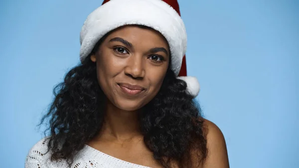 Pleased african american woman in santa hat isolated on blue — Stock Photo