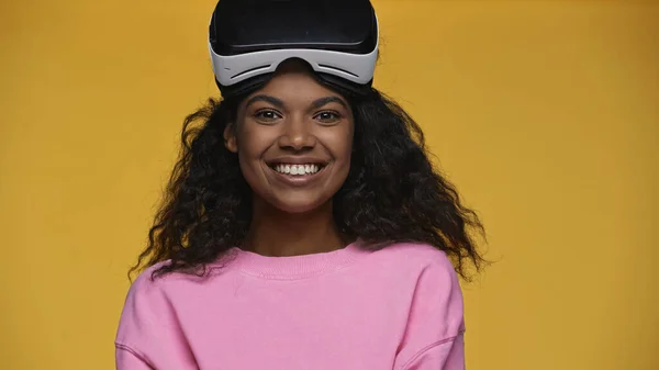Cheerful african american woman in pink sweatshirt and vr headset isolated on yellow - foto de stock