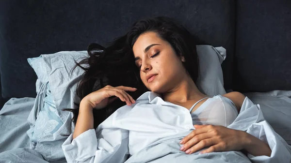 Young woman with closed eyes sleeping in bra and shirt — стоковое фото