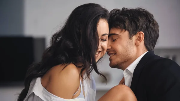 Cheerful businessman in suit kissing girlfriend with closed eyes — Stock Photo