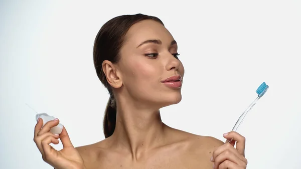 Portrait of brunette young woman looking at toothbrush isolated on white — Photo de stock