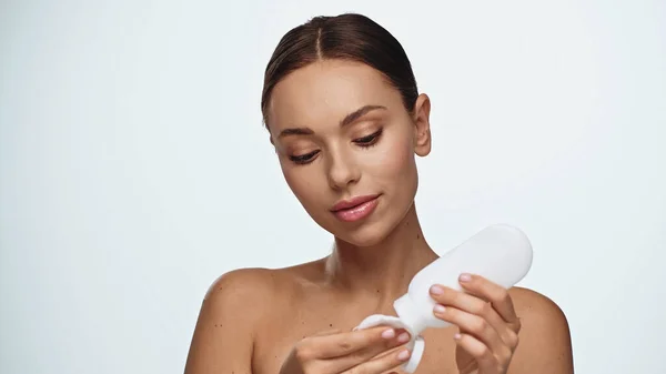 Retrato de morena jovem aplicando produto cosmético na almofada de algodão isolado no branco — Fotografia de Stock