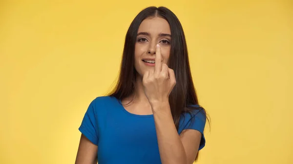 Young and cheerful woman in blue t-shirt showing middle finger isolated on yellow — Stock Photo