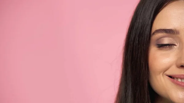 Vista cortada de mulher morena feliz com maquiagem e olho fechado isolado em rosa — Fotografia de Stock