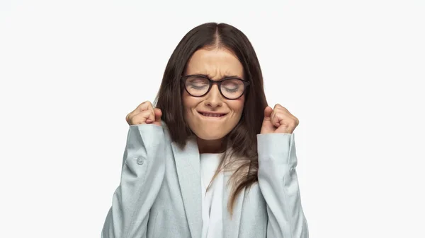 Successful businesswoman in grey blazer and eyeglasses biting lip and rejoicing isolated on white — Stockfoto