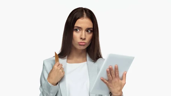 Pensive businesswoman in grey blazer holding credit card and digital tablet isolated on white — Foto stock