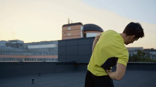 Young brunette sportsman working out on roof in evening — Stock Photo