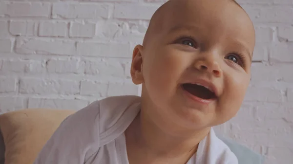 Close up of adorable baby laughing near white brick wall — Stock Photo