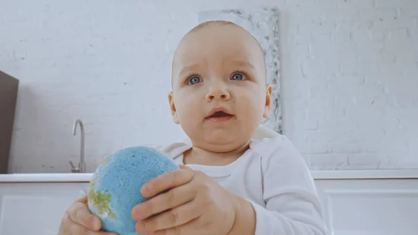 Cute toddler girl with blue eyes holding small globe — Stock Photo