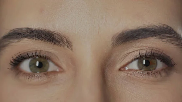 Close up view of woman with hazel eyes and mascara on eyelashes looking at camera — стоковое фото