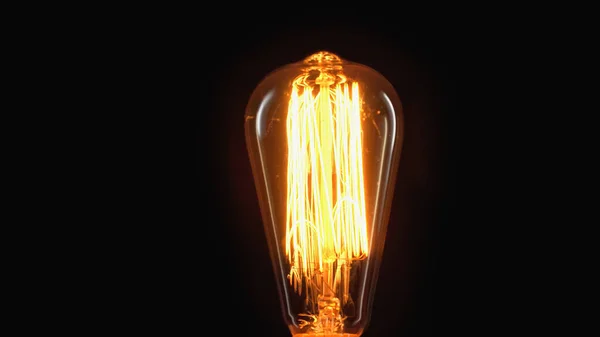 Incandescent light bulb switched on isolated on black with copy space — Stock Photo