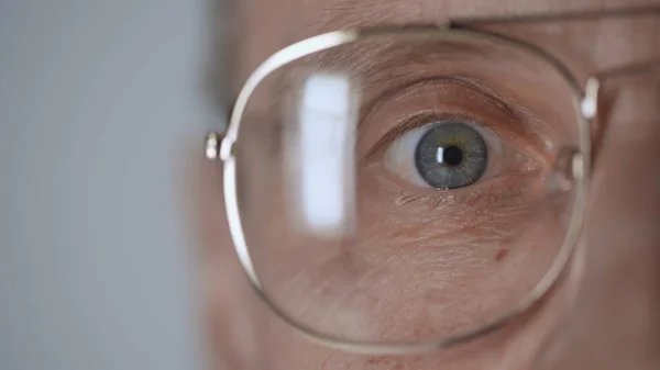 Cropped view of middle aged man with blue eye and eyeglasses looking at camera isolated on grey — Foto stock