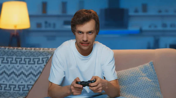 KYIV, UKRAINE - MARCH 12, 2019: tensed young man playing video game in living room — Stock Photo