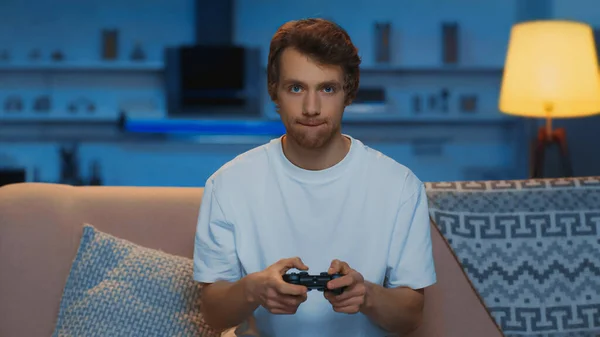 KYIV, UKRAINE - MARCH 12, 2019: concentrated young man playing video game in living room — Foto stock