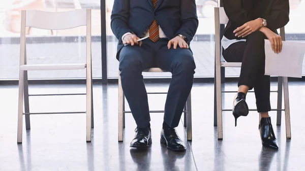 Cropped view of man and woman waiting for job interview in office - foto de stock