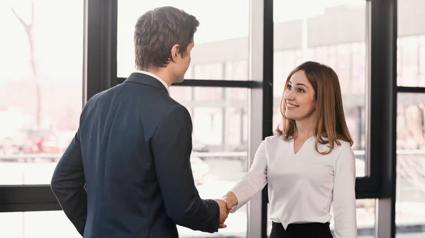 Businessman shaking hands with cheerful woman after job interview — Stockfoto