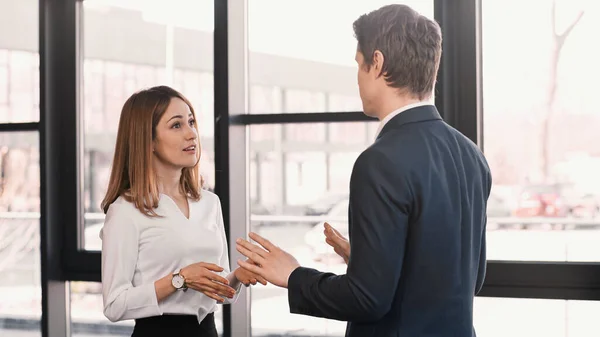 Businessman and smiling woman gesturing during conversation on job interview — стоковое фото