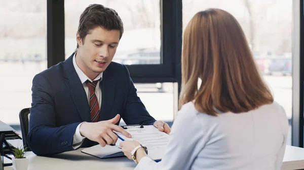 Man pointing at resume during job interview with businesswoman in office — стоковое фото