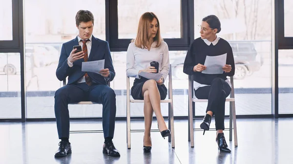 Woman with coffee to go sitting near job seekers with resumes in office — Foto stock