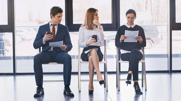 Job seekers with resumes sitting near woman with takeaway drink in office — Foto stock