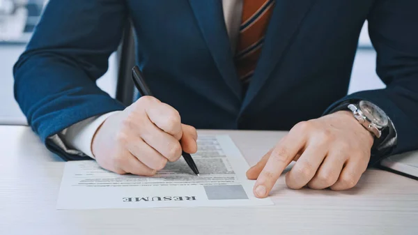 Cropped view of businessman filling in resume before job interview in office — стоковое фото