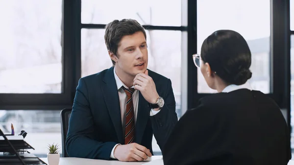 Attentive businessman listening to brunette woman during job interview — Stockfoto