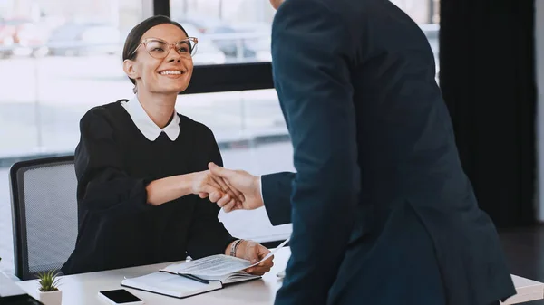 Smiling businesswoman holding resume and shaking hands with man after job interview — Stock Photo