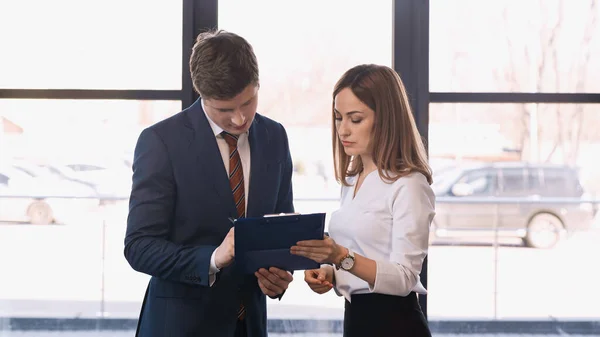 Woman holding clipboard with cv near businessman during job interview — Stock Photo