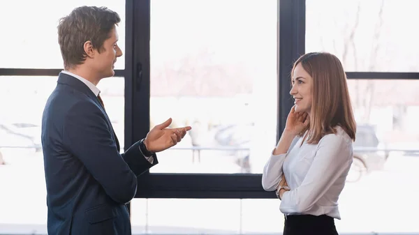 Side view of employer pointing with hand while talking to positive woman on job interview - foto de stock