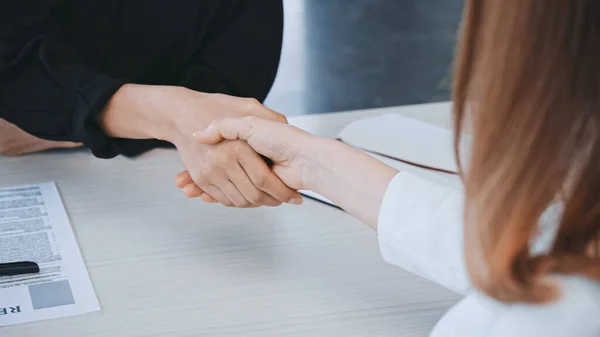 Cropped view of employer and job seeker shaking hands near resume in office — стоковое фото