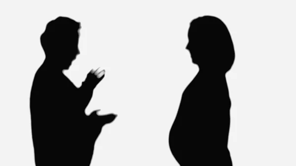 Silhouette of pregnant woman near surprised friend showing wow gesture isolated on white - foto de stock