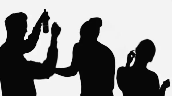 Shadow of man with bottle of beer near silhouettes of dancing friends isolated on white — стоковое фото