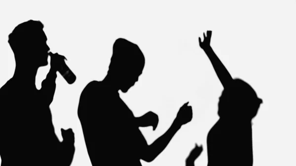 Black shadows of friends dancing near man drinking beer isolated on white — Stock Photo
