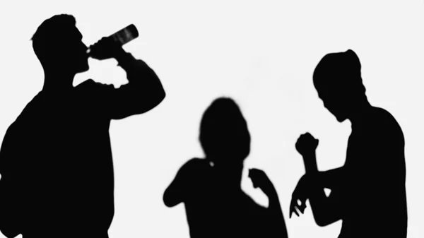 Silhouette of man drinking beer near dancing friends isolated on white — Stock Photo