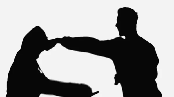 Shadow of man punching robber in hood isolated on white - foto de stock