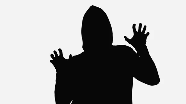 Black shadow of maniac in hood showing frightening gesture isolated on white — стоковое фото